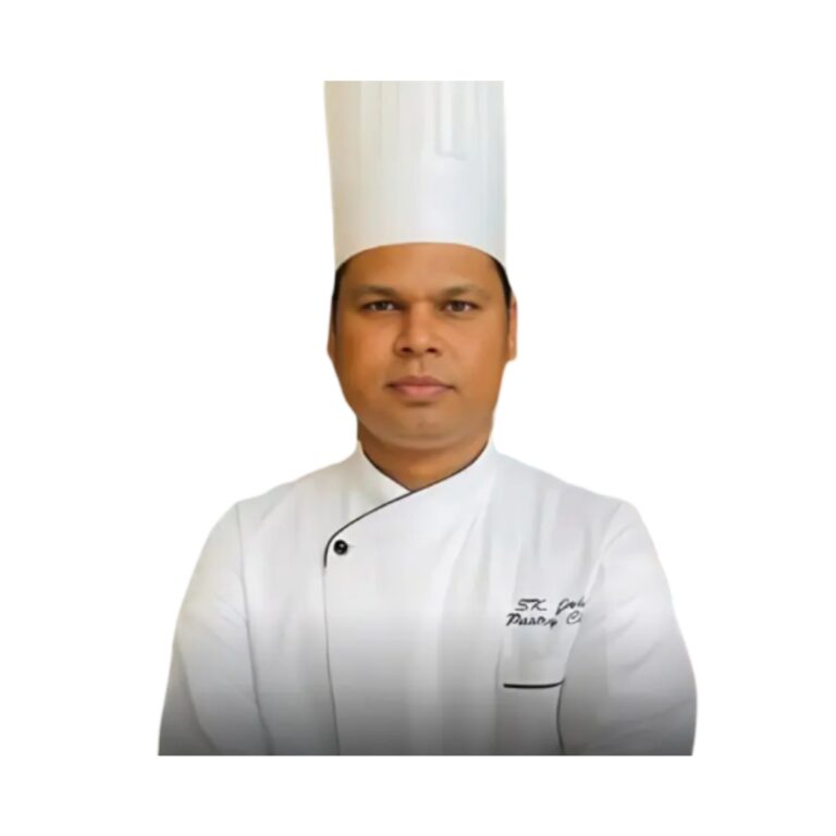 Professional chef in a white uniform and tall white hat, facing the camera with arms crossed.