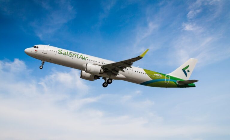 SalamAir passenger jet in white livery with a green-blue tail flying against a blue sky with some clouds.