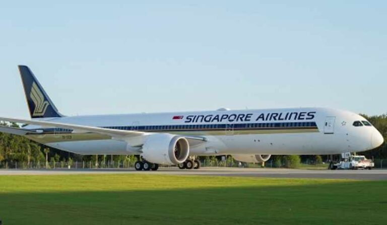 Singapore Airlines wide-body aircraft on taxiway with white fuselage and blue-gold livery, tail fin logo visible in background.
