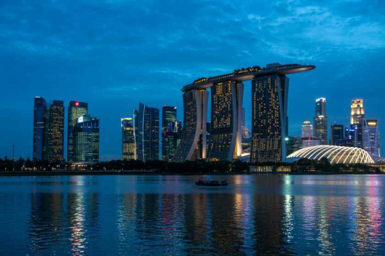 Nighttime view of Singapore skyline featuring Marina Bay Sands and the ArtScience Museum reflecting on the bay at dusk.