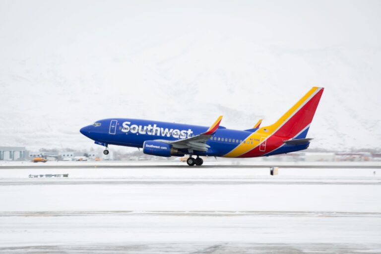 Southwest Airlines plane on a snow-covered runway, blue fuselage and colorful red-yellow tail gleaming in winter light.