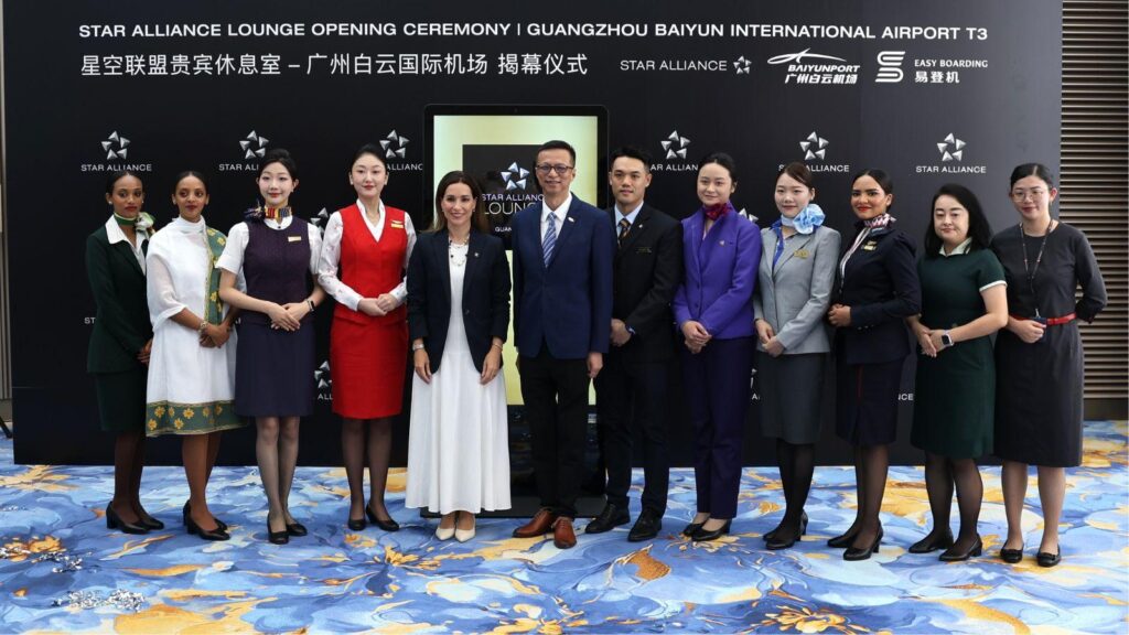Group of staff posing for a photo at the Star Alliance Lounge opening ceremony at Guangzhou Baiyun International Airport, fronted by a black backdrop with logos and text.