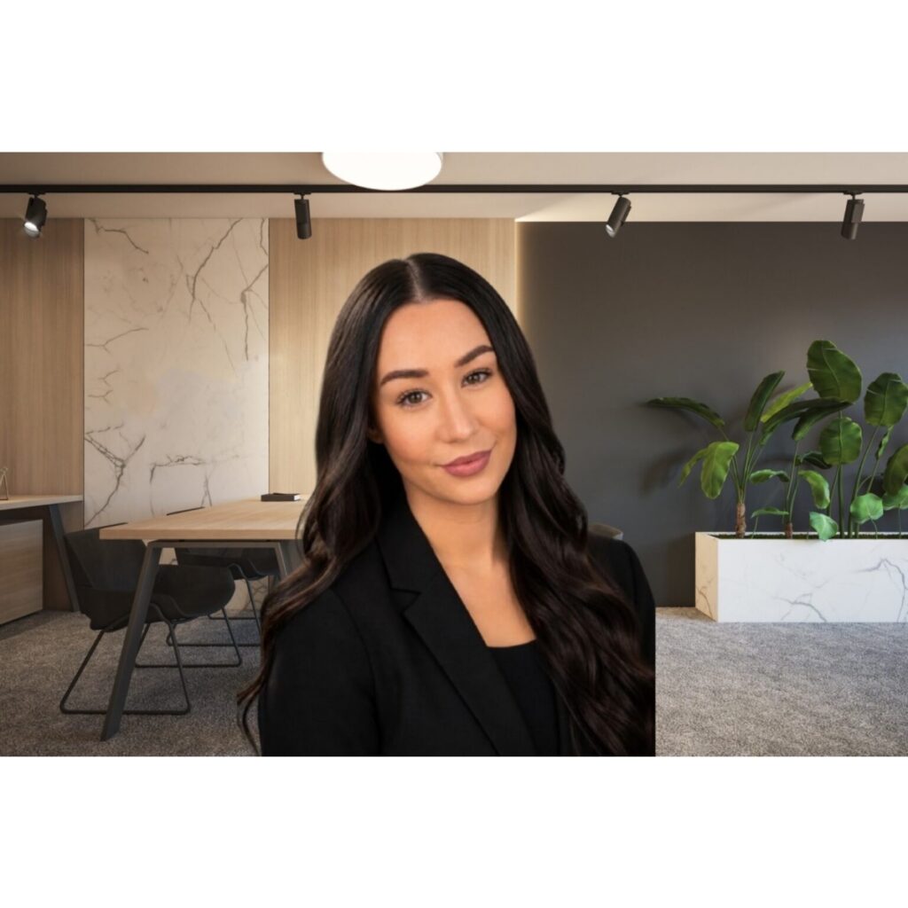 Professional woman in a black blazer standing in a modern office lounge with marble accents.