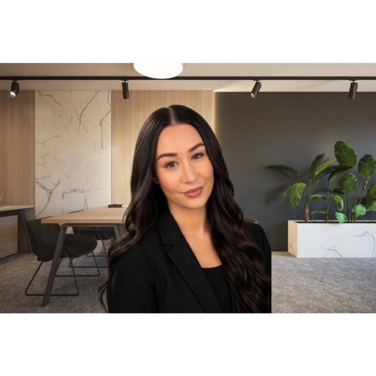 Professional woman in a black blazer standing in a modern office lounge with marble accents.