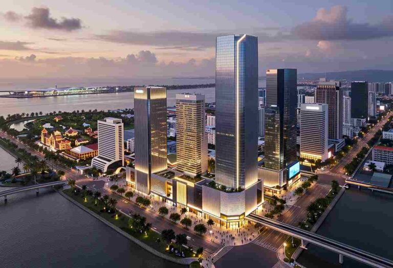 Skyline of modern glass skyscrapers illuminated at dusk along a waterfront city district.