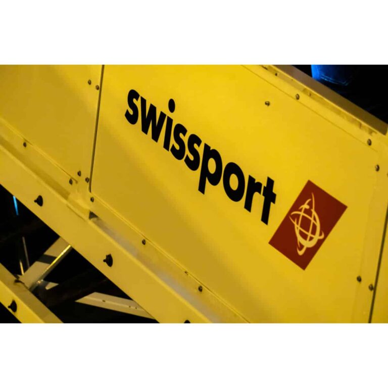 Close-up of a yellow industrial panel with the black word 'Swissport' and a red square logo, indicating airport ground support equipment.