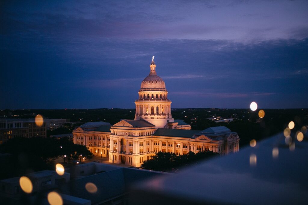 Twilight view of a grand domed capitol building illuminated in warm lights.