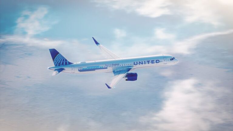 Airplane in flight with United branding cruising above fluffy clouds, blue sky visible around the fuselage and wings