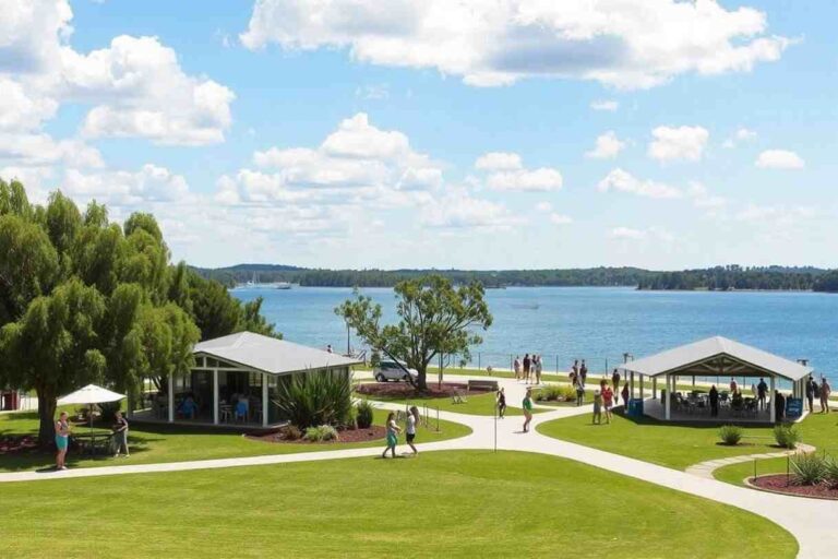 Lakeside park with two white pavilions, walking paths, and people enjoying a sunny day by the blue lake.