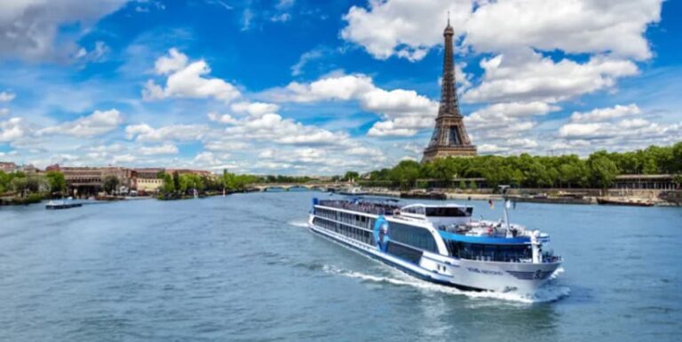 Passenger river cruise boat gliding along the Seine with the Eiffel Tower and trees in the background, under a blue sky with scattered clouds.