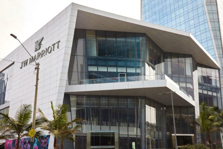 JW Marriott hotel exterior with a modern angular glass facade and palm trees in front.