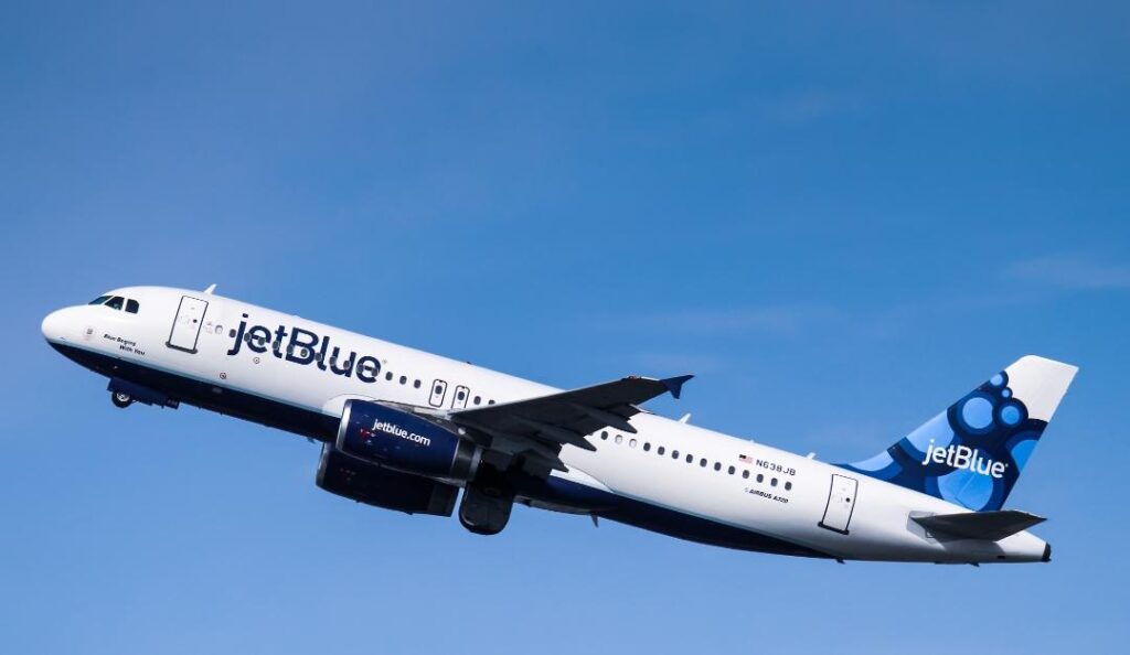 JetBlue airplane in flight against a clear blue sky, branding visible along the fuselage and blue-tail livery.