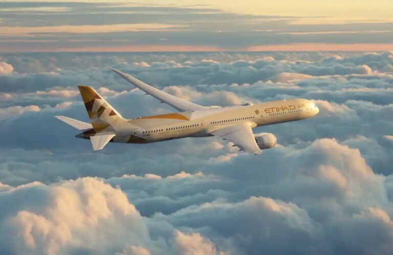 Etihad Airways passenger jet flying above fluffy clouds at sunset/sunrise light