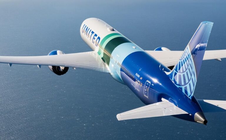 United Airlines aircraft in blue and teal livery banking over the ocean during flight.