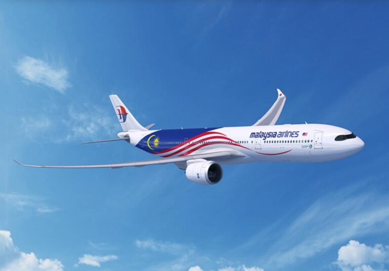 Malaysia Airlines jet in midflight against a clear blue sky with wispy clouds to the left.
