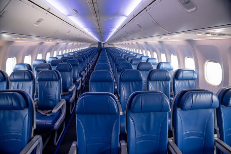 Interior of a blue airplane cabin with rows of blue leather seats extending toward the back.