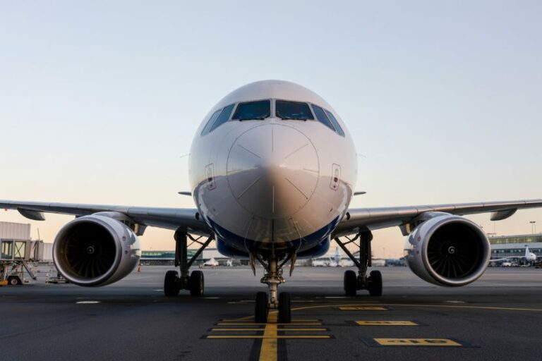 Front view of a large commercial airplane on the tarmac, engines on both wings and landing gear visible.