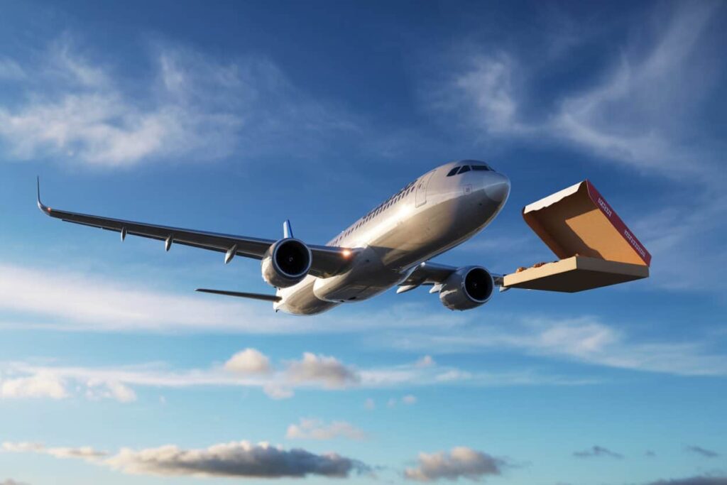 Air cargo airplane flying in the blue sky with a large cardboard box on a delivery chute attached to the plane (package delivery visualization).
