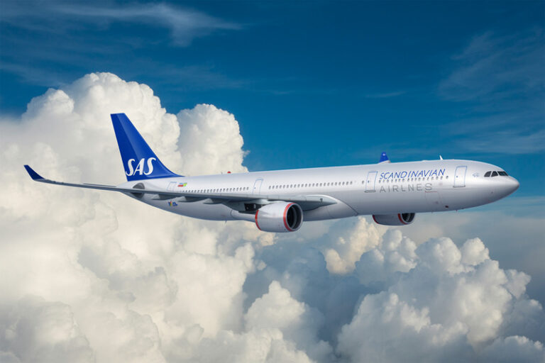 SAS airliner flying above fluffy white clouds against a blue sky.