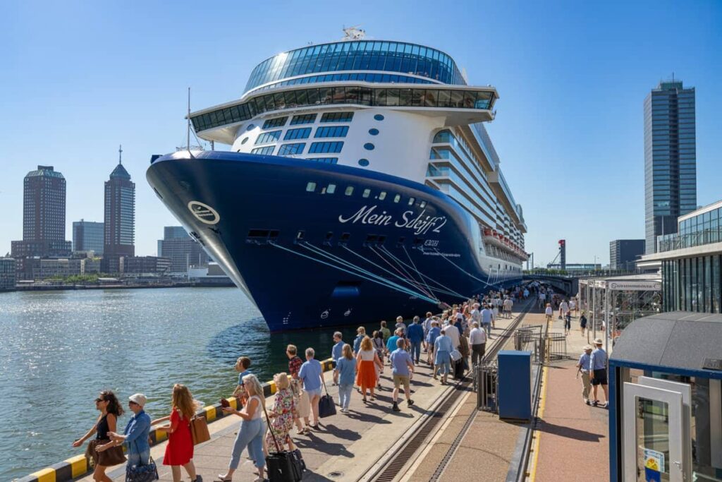 Cruise ship Mein Schiff docked at a modern port as passengers walk along the gangway area by the water