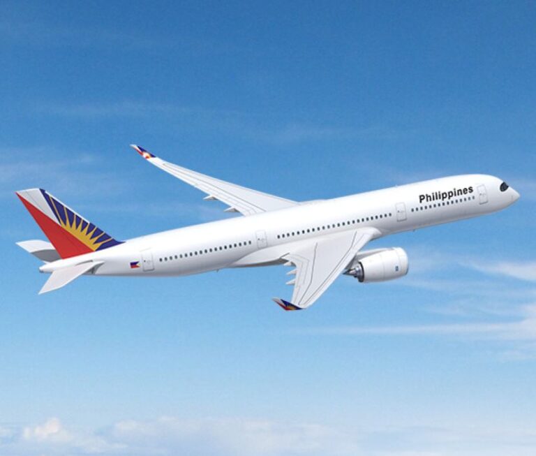 White commercial airplane in flight with Philippines livery against a blue sky, tail featuring a colorful geometric design.