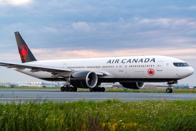 Air Canada wide-body jet taxiing on runway, white fuselage with red maple leaf logo on tail, engines visible under wings