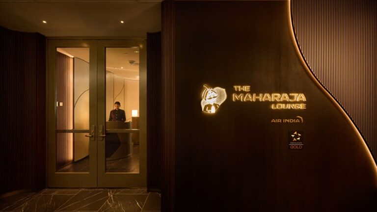 Entrance to The Maharaja Lounge with a receptionist behind a desk and a glowing lounge sign on a dark curved wall.