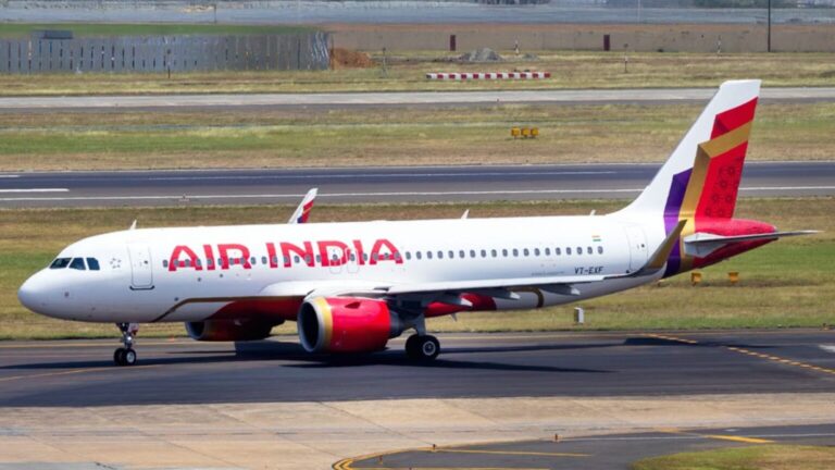 Air India passenger jet taxiing on runway with colorful tail design and red engine nacelles in clear day.