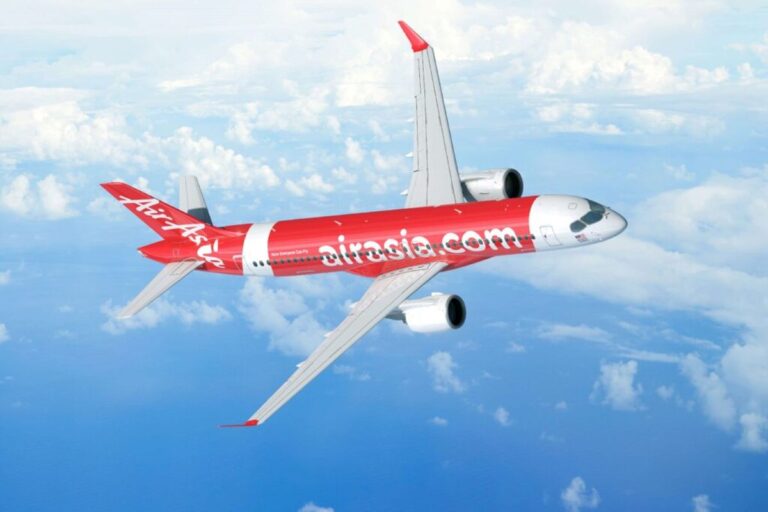 AirAsia airliner in red livery flying above clouds, fuselage branded with airasia.com.