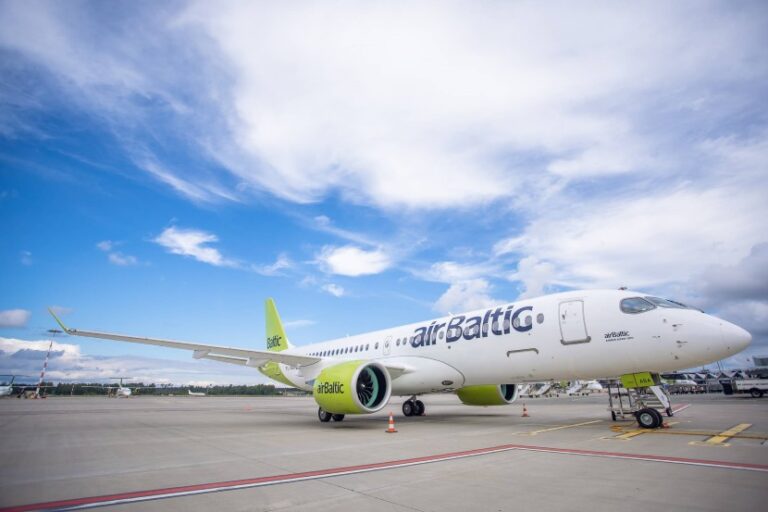 AirBaltic passenger jet on a tarmac with a blue sky and clouds above.