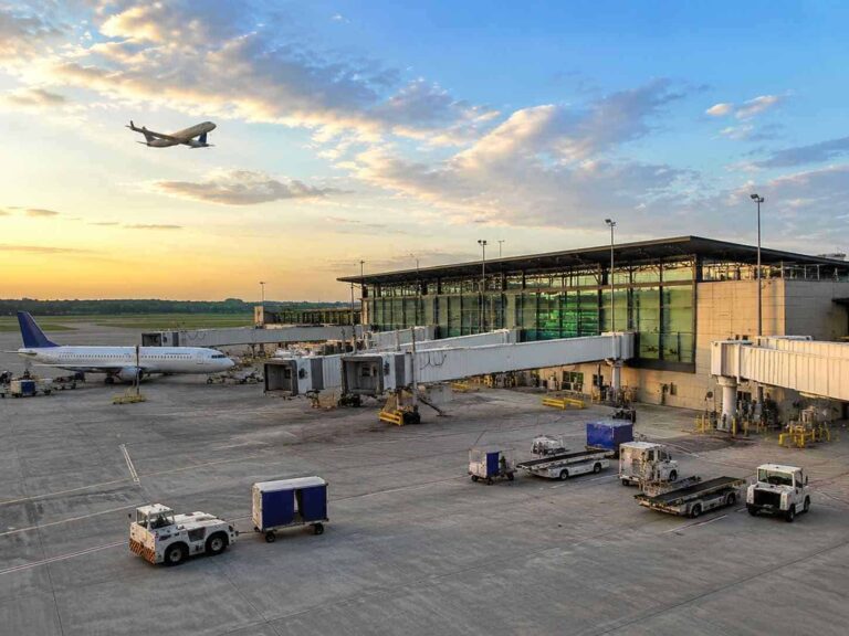 Jet bridge connected to a parked plane at the gate on the tarmac at sunset.