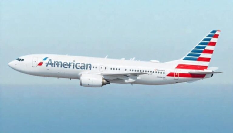 Commercial airliner in flight with American Airlines livery against a light blue sky.