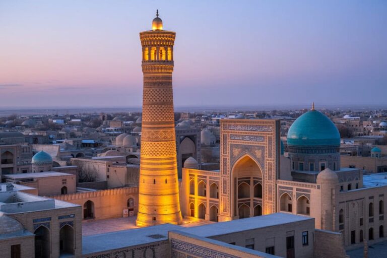 Tall illuminated minaret beside a grand blue-domed mosque at sunset in a historic Middle Eastern cityscape.