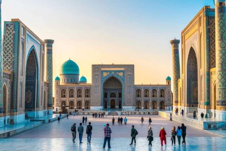 People walk in a large plaza in front of a grand Islamic building with turquoise domes and ornate tilework.