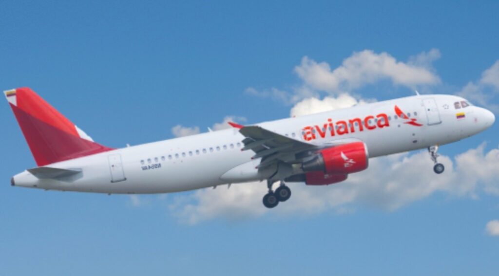 Avianca passenger airplane taking off, white fuselage with red logo against a blue sky with clouds, landing gear down