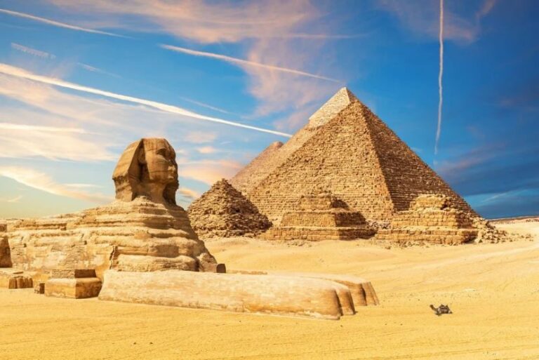 Sphinx and pyramids at Giza in a sandy desert under a blue sky with wispy clouds.
