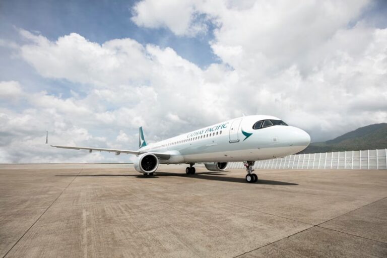 Cathay Pacific airliner parked on a clear apron with mountains in the background.