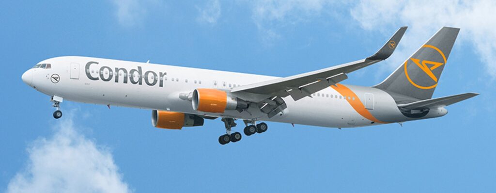 Condor passenger jet in flight against a blue sky, with orange engine nacelles and tail logo visible.