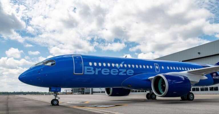 Blue Breeze airliner parked on the airport tarmac with engines and nose gear visible under a partly cloudy sky.