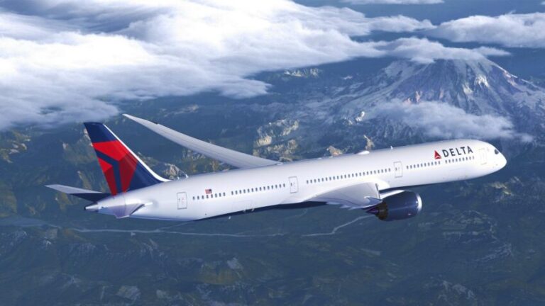 Delta Air Lines wide-body jet flying above mountains and clouds in daylight import.