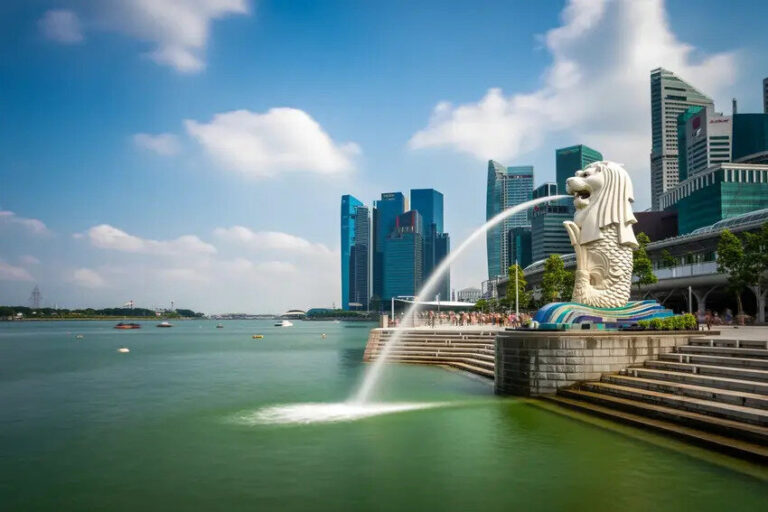 Merlion statue spouting water into Marina Bay with Singapore's skyline in the background.