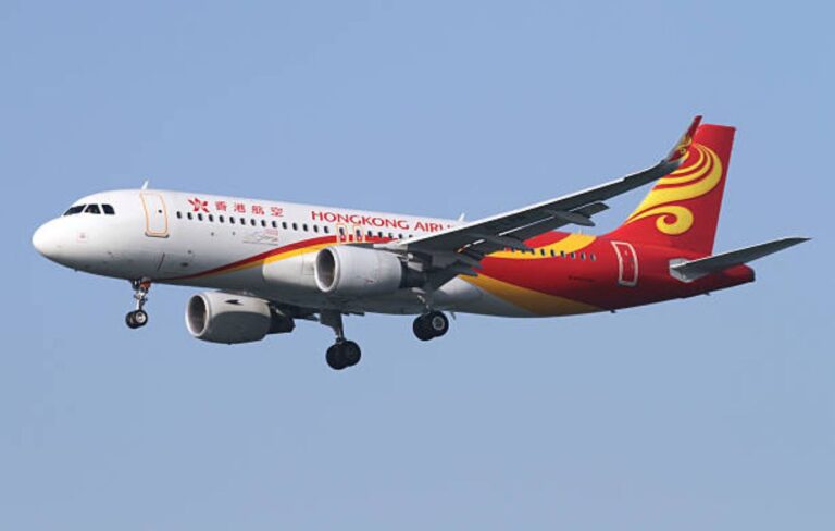 Hong Kong Airlines passenger jet in a clear blue sky with landing gear deployed.