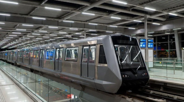 Silver modern metro train at an empty station platform, illuminated ceiling lights above, doors closed.