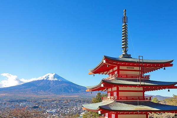 Red five-story pagoda in the foreground with Mount Fuji and a clear blue sky in the background, Japan.