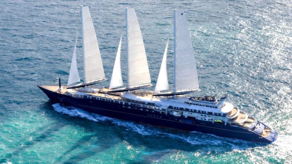 Luxurious four-masted sailing yacht with white sails and a dark hull gliding through turquoise ocean water.]','Luxurious four-masted schooner cruising on blue-green sea, white decks and multiple decks visible.