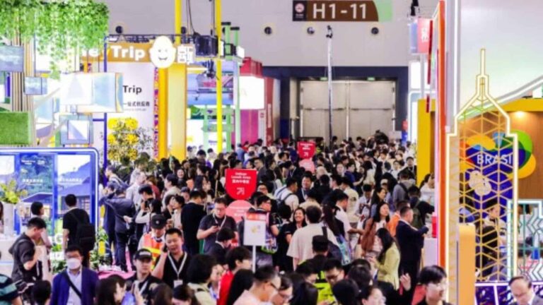 Large crowd of attendees at a colorful expo hall with bright booths and signage, including H1-11 and a Brazil-themed display in the foreground.