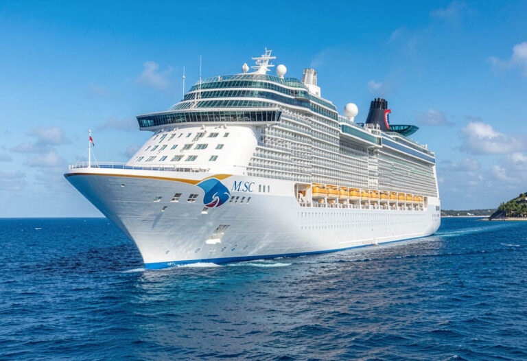 Large white MSC cruise ship on a calm blue ocean, with multiple decks and yellow lifeboats visible along the side.