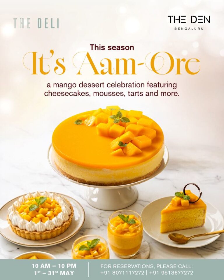 Mango dessert spread with a large mango cheesecake on a stand, plus mango tarts and mousse cups on a marble surface.