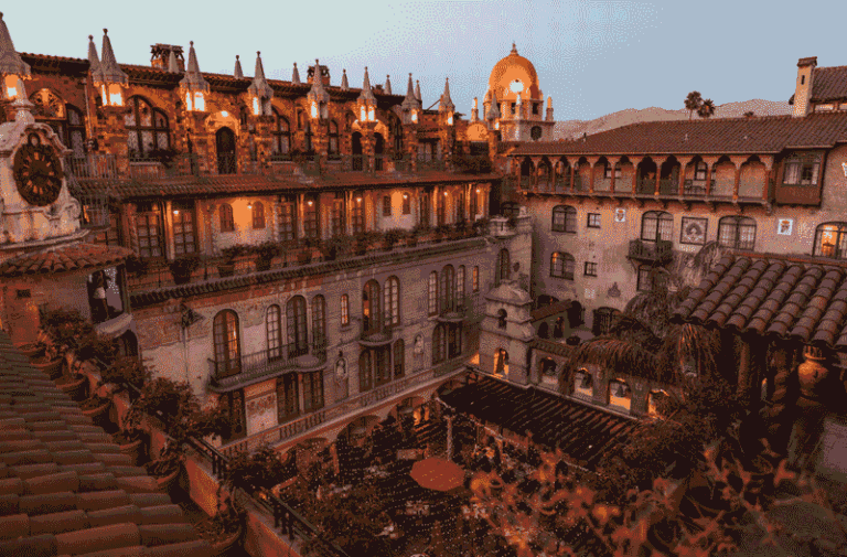 Mediterranean-style hotel courtyard at dusk with string lights and arched balconies of warm stone architecture
