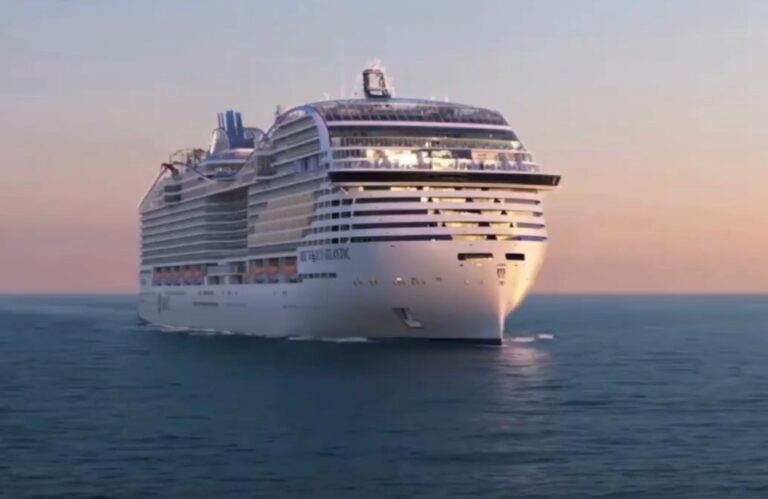 Large white cruise ship sailing on calm blue sea at sunset.